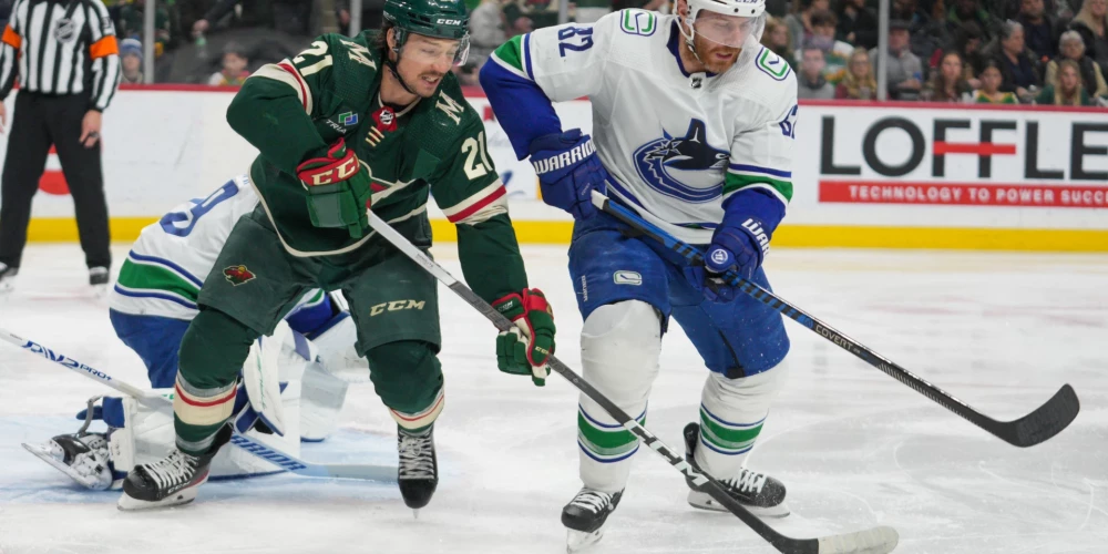 Feb 19, 2024; Saint Paul, Minnesota, USA; Minnesota Wild right wing Brandon Duhaime (21) and Vancouver Canucks defenseman Ian Cole (82) fight for possession in front of the Vancouver Canucks net in the second period at Xcel Energy Center. Mandatory Credit: Matt Blewett-USA TODAY Sports