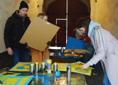 VIDEO un FOTO: Ukrainas atbalstītāji darbnīcā rada plakātus, ar kuriem dosies pie Brīvības pieminekļa