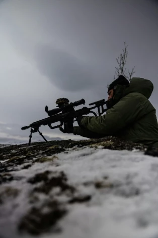 Nīderlandes jūras kājnieks novēro Sandstrandas, Norvēģijas pludmali, kad desanta kuģis tuvojas krastam vingrinājuma "Nordic Response" 24 ietvaros.