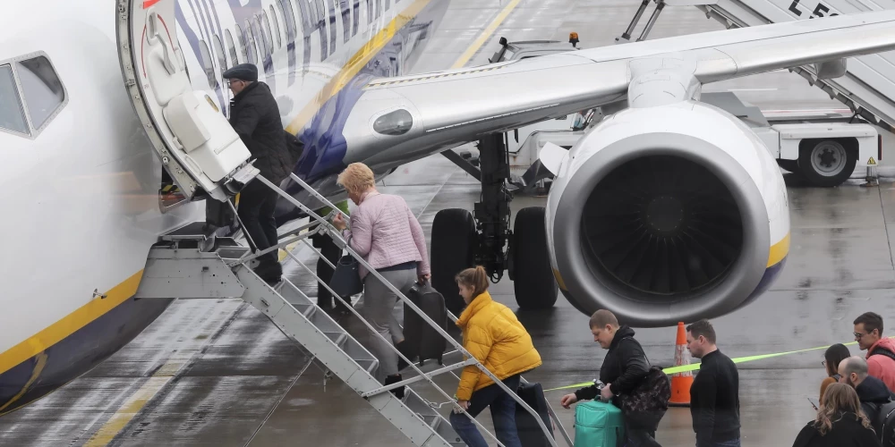 Пассажиры с ручной кладью садятся в самолет. (Фото: LETA)