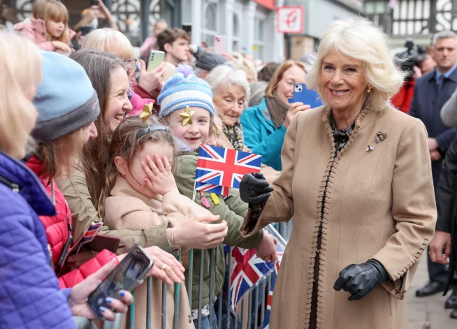 Queen Camilla smiles as she meets a young well-wisher, who places her hand over her face, during the visit to the Farmers' Market on March 27, 2024 in Shrewsbury, England.