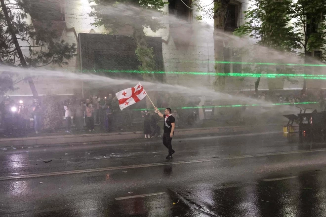 Protestētājs ar Gruzijas karogu nebaidās no policijas pielietotā ūdensmetēja.