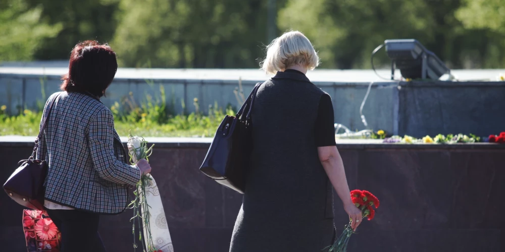 Sievietes noliek ziedus pie pieminekļa "Padomju Latvijas un Rīgas atbrīvotājiem no nacistiskajiem iebrucējiem" biedrības "9. maijs.lv" rīkotā 2. Pasaules kara piemiņas pasākuma laikā Uzvaras parkā./2018. gada 8. maijs.