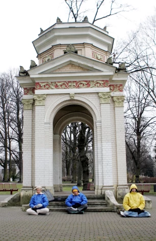 Cilvēki meditē Rīgas jubilejas paviljona pakājē.