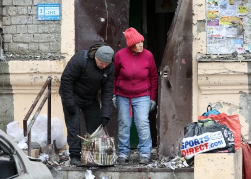 Harkivas iedzīvotāji pie Krievijas raķešu uzlidojumā izpostītas dzīvojamās ēkas.