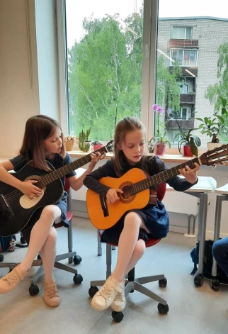 Dvīņu māsas apgūst ģitārspēli Ādažu mākslas un mūzikas skolā.