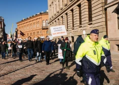 Juris Lazdiņš redzams ar krustu rokās Doma laukumā aiz Valsts policijas darbiniekiem