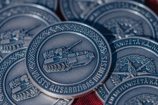 На аверсе памятной монеты изображена бронетехника БМРД, символизирующая механизированную пехотную бригаду сухопутных войск, и выгравирована надпись "Valsts aizsardzības dienests" ("Служба государственной обороны)".