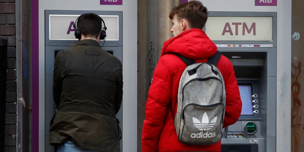 Cilvēki izmanto bankomātu pie "Allied Irish Bank" filiāles Dublinā.
