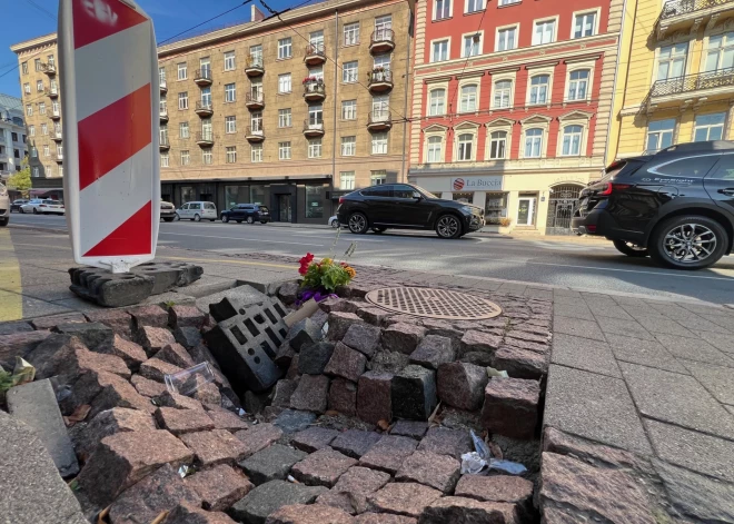 FOTO: mājas iedzīvotāji ar ziediem svin bedres jubileju Rīgas centrā — Rīgas dome rausta plecus 