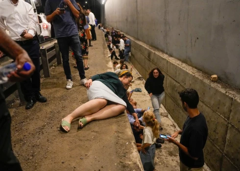 Izraēlas iedzīvotāji slēpjas ceļmalā Irānas raķeštrieciena laikā (foto: Scanpix / AP)