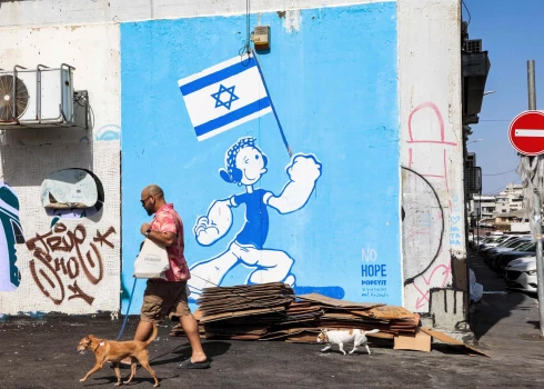  Vīrietis ved savus suņus garām grafiti, Telavivā, 2024. gada 14. oktobrī, kara starp Izraēlu un Hamas Gazas joslā laikā.