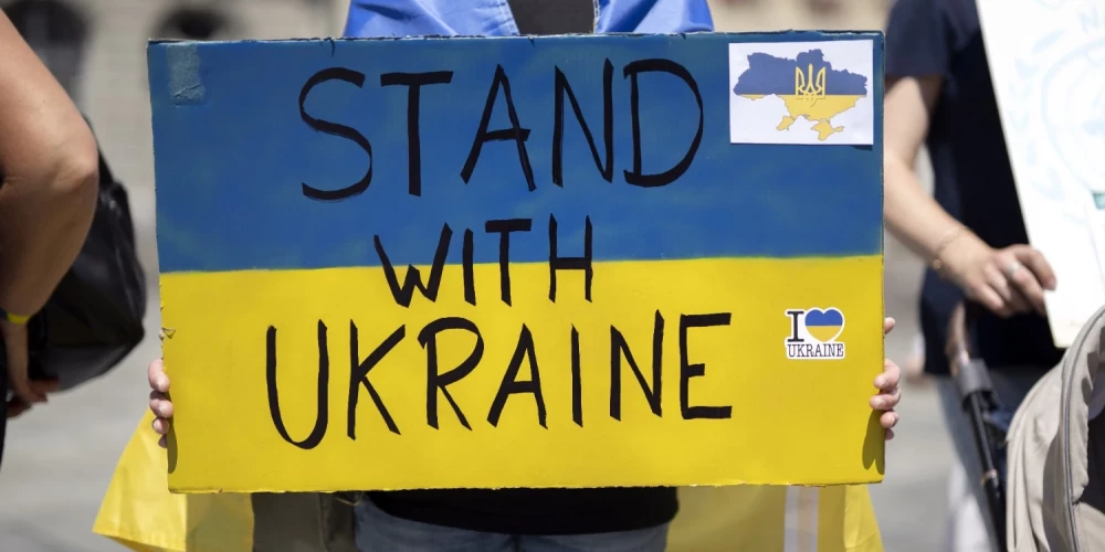 Uzraksts angļu valodā "Stand with Ukraine" (Es atbalstu Ukrainu). 