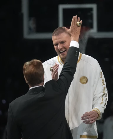 Kristaps Porziņģis ar NBA čempionu gredzenu pirkstā runājas ar kluba īpašnieku Stīvu Paljuku.