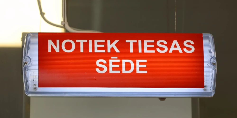 Uzraksts "Notiek tiesas sēde". 