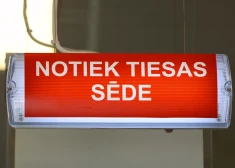 Uzraksts "Notiek tiesas sēde". 