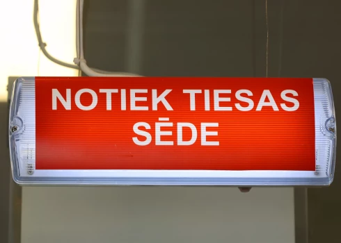 Uzraksts "Notiek tiesas sēde". 