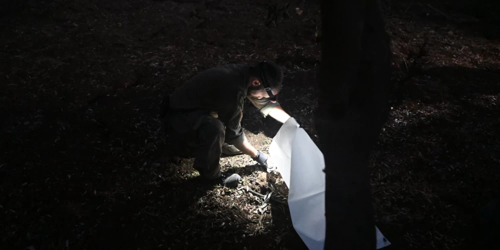 Izraēlas drošības spēku darbinieks strādā vietā, kur Libāna trāpīja ar raķetēm.