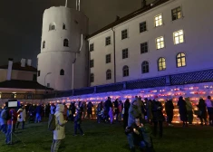 Cilvēki pie Rīgas pils mūra iededz svecītes .
