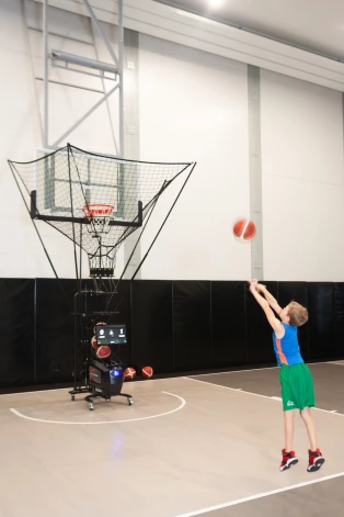 Īpašs bonuss šajā zālē ir speciāla bumbu padošanas iekārta jeb shooting machine. “Kad palīdzēju Tomasam trenēties, viņš jau teica: “Tēti, man nevajag šūtingmašīnu, jo tu jau man esi tās vietā, tu padod bumbas vislabāk.” Taču darba dēļ es ļoti bieži neesmu mājās, man jādodas tiesāt spēles, un kas tad pados Tomasam bumbas? Tāpēc mums vajadzēja šādu iekārtu, lai trenējoties metienu skaits nebūtu 200, bet visi 500 stundā,” skaidro Oļegs.