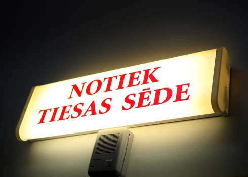 Uzraksts "Notiek tiesas sēde" .