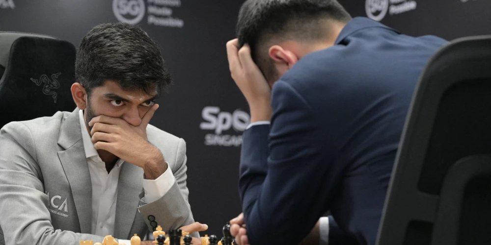 18 gadus vecais Gukešs Dommaradžu vēro pārdomās ieslīgušo pretinieku, pasaules čempionu Dinu Ližeņu