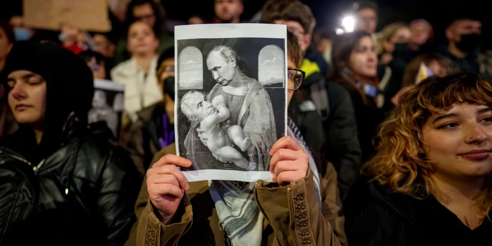 Demonstrante Bukarestē tur plakātu, kur parādīta Kelina Džordžesku saikne ar Kremļa diktatoru Vladimiru Putinu (foto: Scanpix / AP)