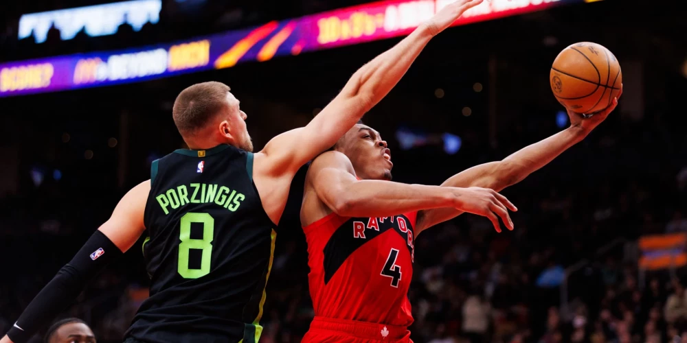 Kristaps Porziņģis mēģina apturēt Toronto "Raptors" līderi Skotiju Bārnsu.