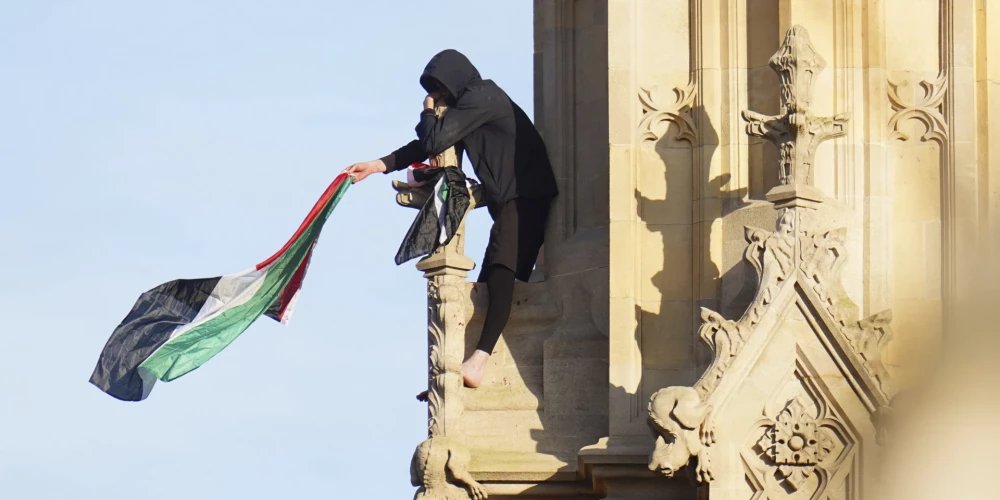 Asiņainām pēdām un ar Palestīnas karogu rokās – protestētājs uzrāpjas uz Bigbena.