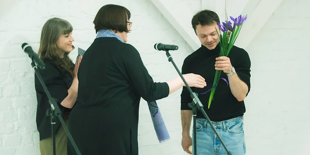 Latvijas Nacionālā mākslas muzeja direktore Māra Lāce pasniedz ziedus māksliniekam Viktoram Timofejevam un sveic viņu ar izstādes atklāšanu.