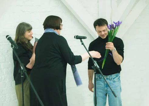 Latvijas Nacionālā mākslas muzeja direktore Māra Lāce pasniedz ziedus māksliniekam Viktoram Timofejevam un sveic viņu ar izstādes atklāšanu.