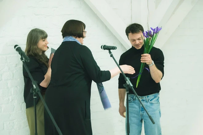 Latvijas Nacionālā mākslas muzeja direktore Māra Lāce pasniedz ziedus māksliniekam Viktoram Timofejevam un sveic viņu ar izstādes atklāšanu.