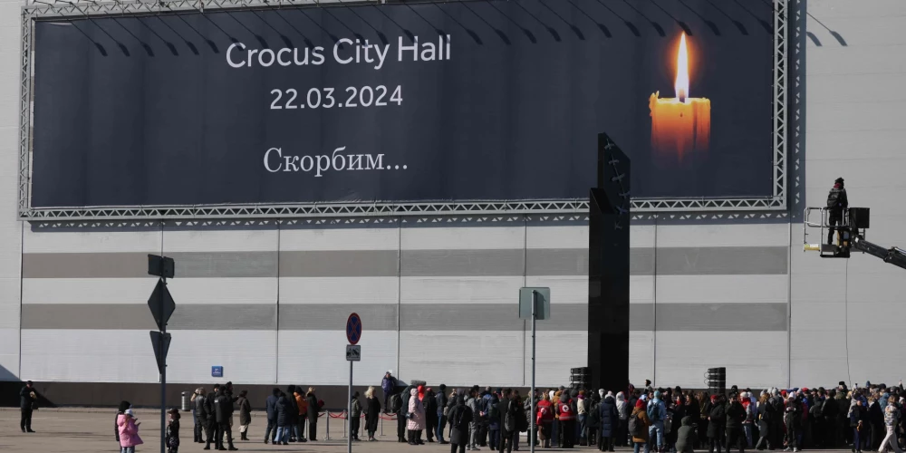 Люди возлагают цветы у Crocus City Hall в память о погибших.
