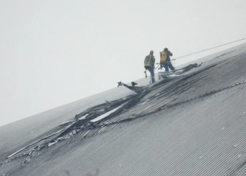 Strādnieki darbojas uz bojātās aizsargnojumes virs 4. reaktora Čornobiļas atomelektrostacijā 2025. gada 14. februārī.