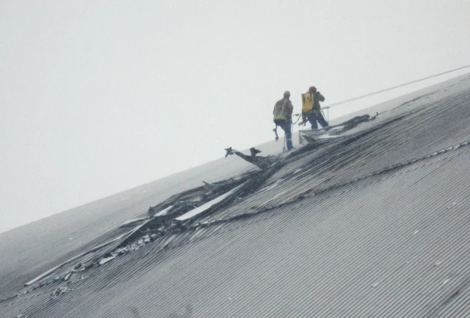 Strādnieki darbojas uz bojātās aizsargnojumes virs 4. reaktora Čornobiļas atomelektrostacijā 2025. gada 14. februārī.