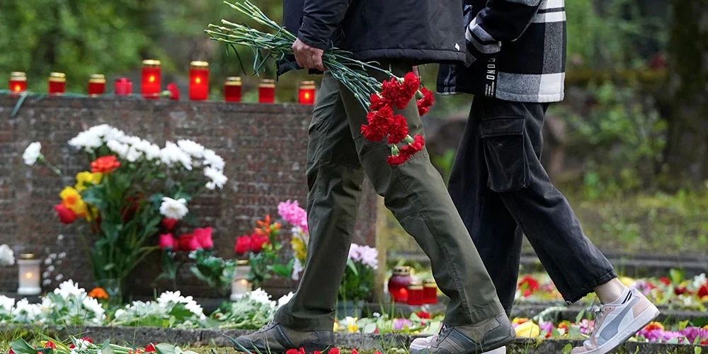 Cilvēki noliek ziedus sarkanās armijas brāļu kapos Pļavniekos. 