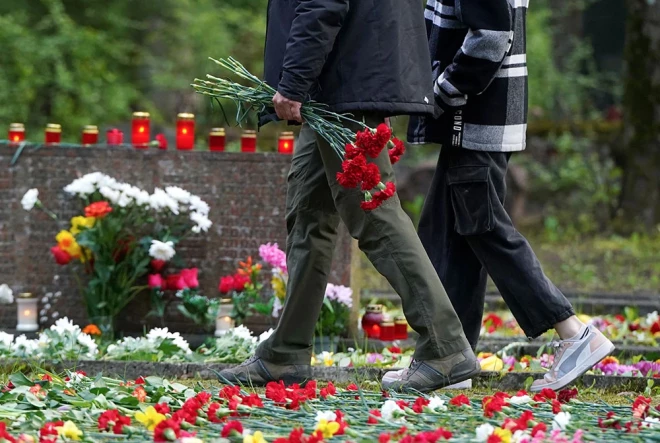 Cilvēki noliek ziedus sarkanās armijas brāļu kapos Pļavniekos.
