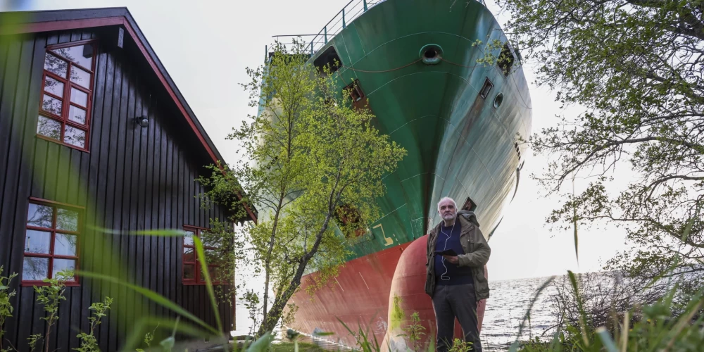 Juhans Helbergs stāv pie savas mājas un negaidītā "ciemiņa" "NCL Salten"