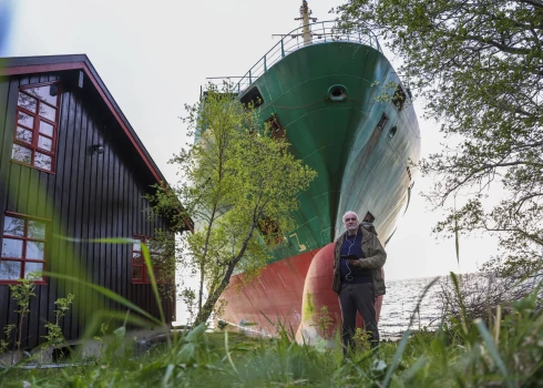 Juhans Helbergs stāv pie savas mājas un negaidītā "ciemiņa" "NCL Salten"