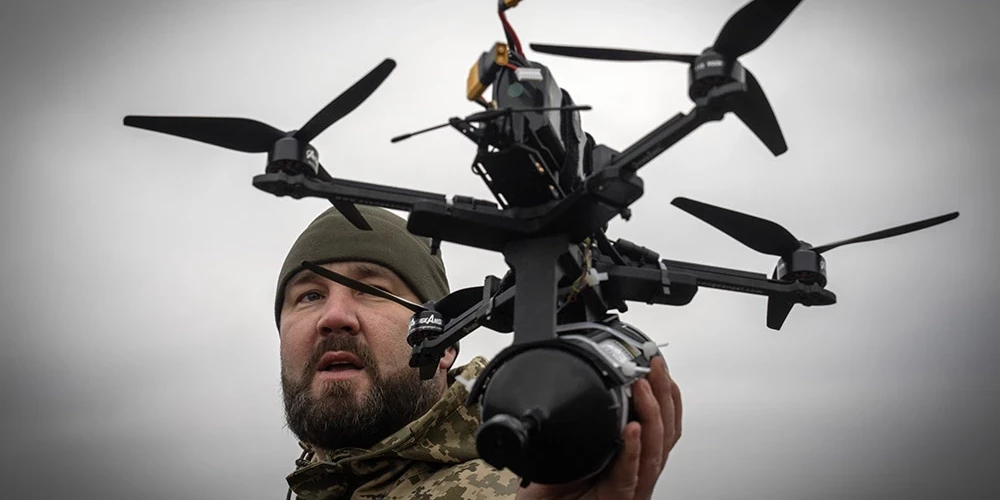 Ukraiņu karavīrs demonstrē Ukrainā radītu optiskās šķiedras dronu.