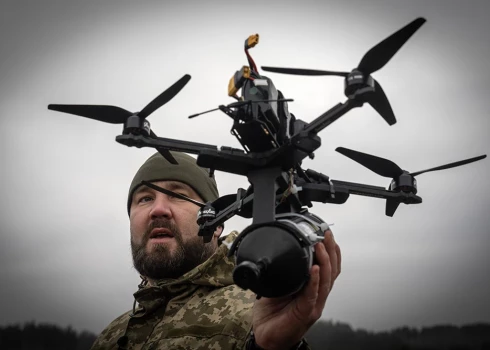 Ukraiņu karavīrs demonstrē Ukrainā radītu optiskās šķiedras dronu.
