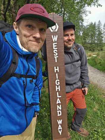 Jānis Aišpurs un Intars Busulis sava pārgājiena sākumā. Ar šādām zīmēm ir nomarķēts "West Highland Way" pārgājienu maršruts, tā ka apmaldīties nav iespējams.