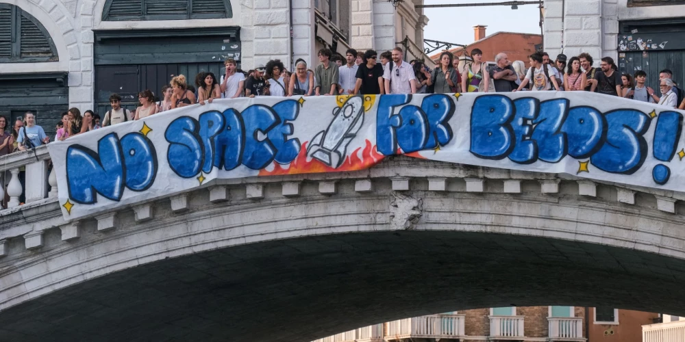 Protestētāji izkāra milzīgu plakātu ar uzrakstu “Šeit nav vietas Bezosam”.