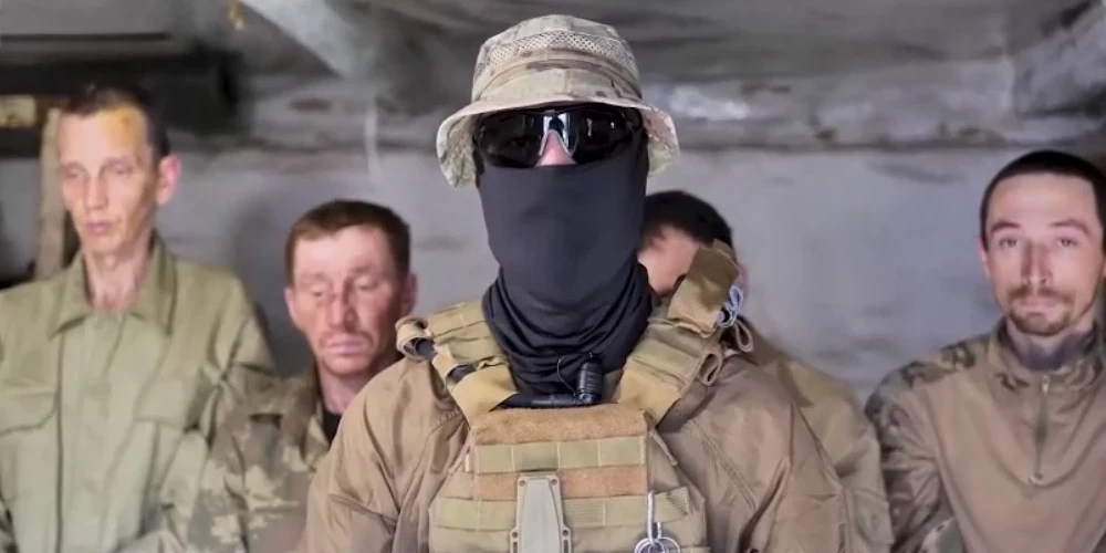 Ukrainas aizstāvis (priekšplānā) ar sagūstītajiem krievu iebrucējiem.