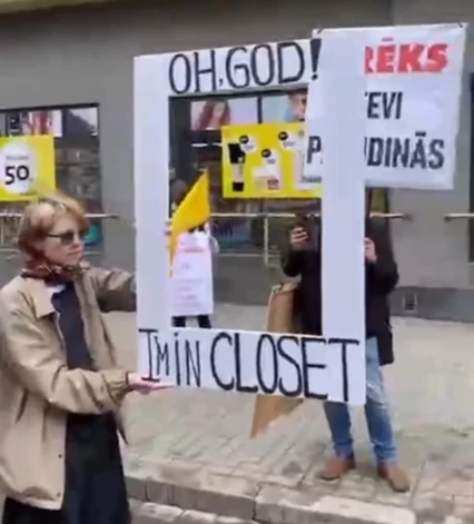 Kāda dalībniece tur izgrieztu rāmi ar uzrakstu “Oh God! I'm in the closet” (latviski – “Ak Dievs! Esmu skapī”) un pieliek to klāt garāmejošajiem praida svinētājiem.