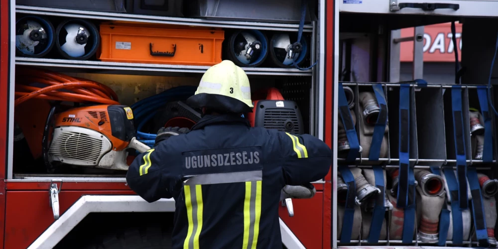 Valsts ugunsdzēsības un glābšanas dienesta ugunsdzēsējs un automašīna. 