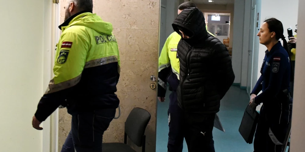 Apsūdzētais Justīnes Reinikovas tēvs Vladimirs Reinikovs (centrā) tiek konvojēts uz tiesas sēdi Latgales rajona tiesā Daugavpilī.