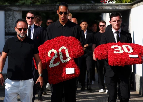 "Liverpool" kapteinis Van Deiks un komandas biedrs Robertson nesa ziedu kompozīcijas sarkanās futbola krekla formās