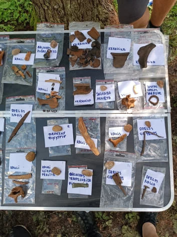 Ieskats arheologu atradumos – gan kauli un keramikas lauskas, gan dzelzs nazis, nagla un sudraba monēta.