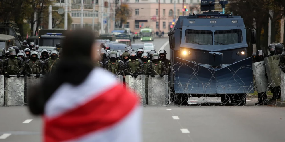 Протестующая стоит перед белорусскими полицейскими, перекрывающими дорогу во время антиправительственного митинга в Минске, Беларусь, 25 октября 2020 года.